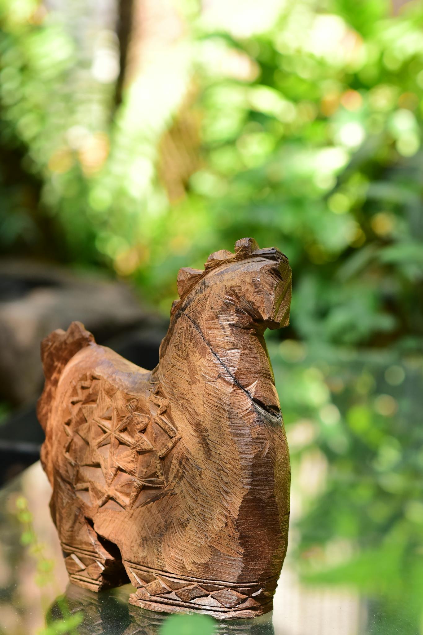 Artistic wooden horse carving in a lush green outdoor setting, capturing natural beauty.