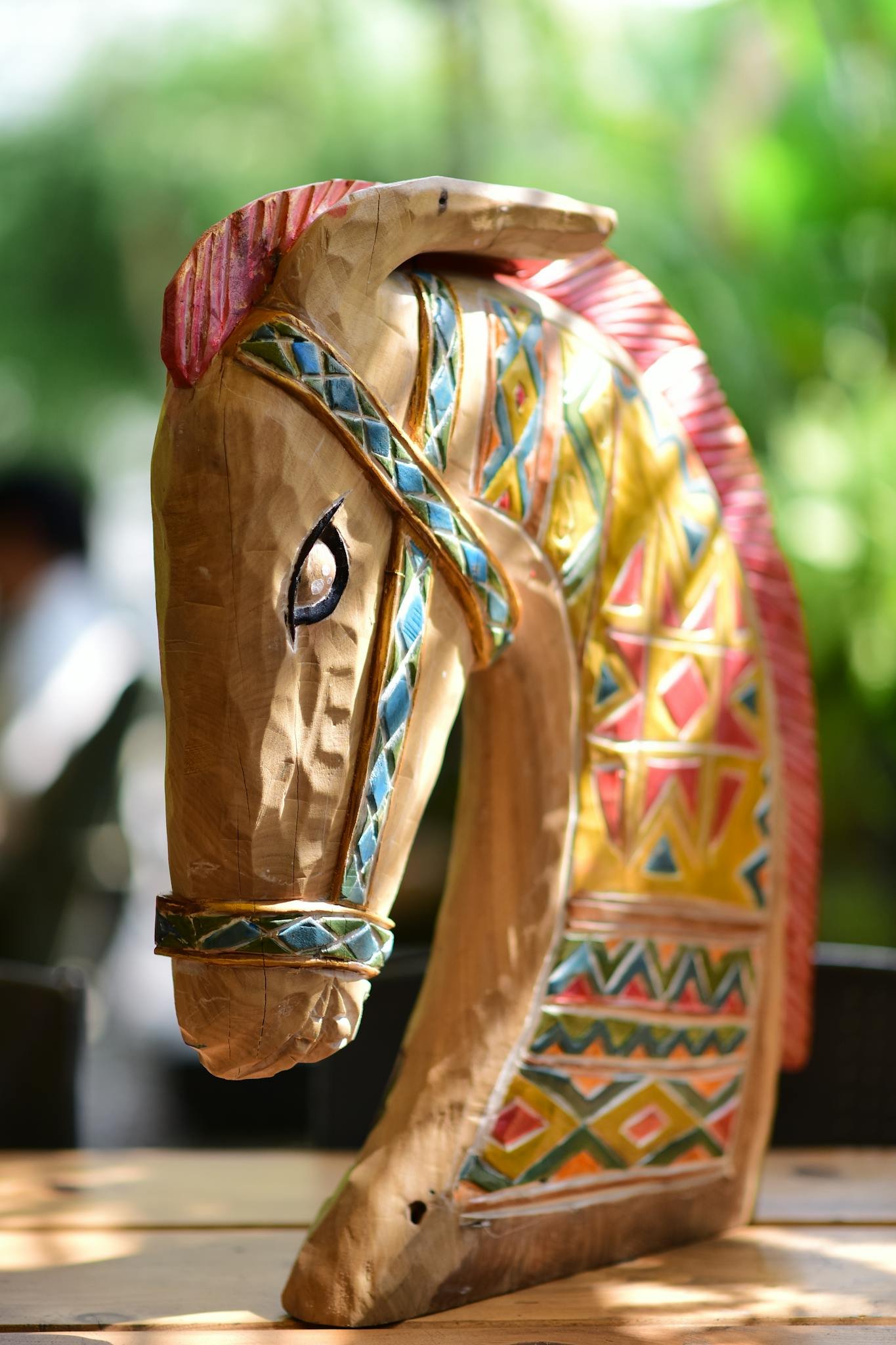 Vibrant hand-carved wooden horse head with tribal patterns on display.